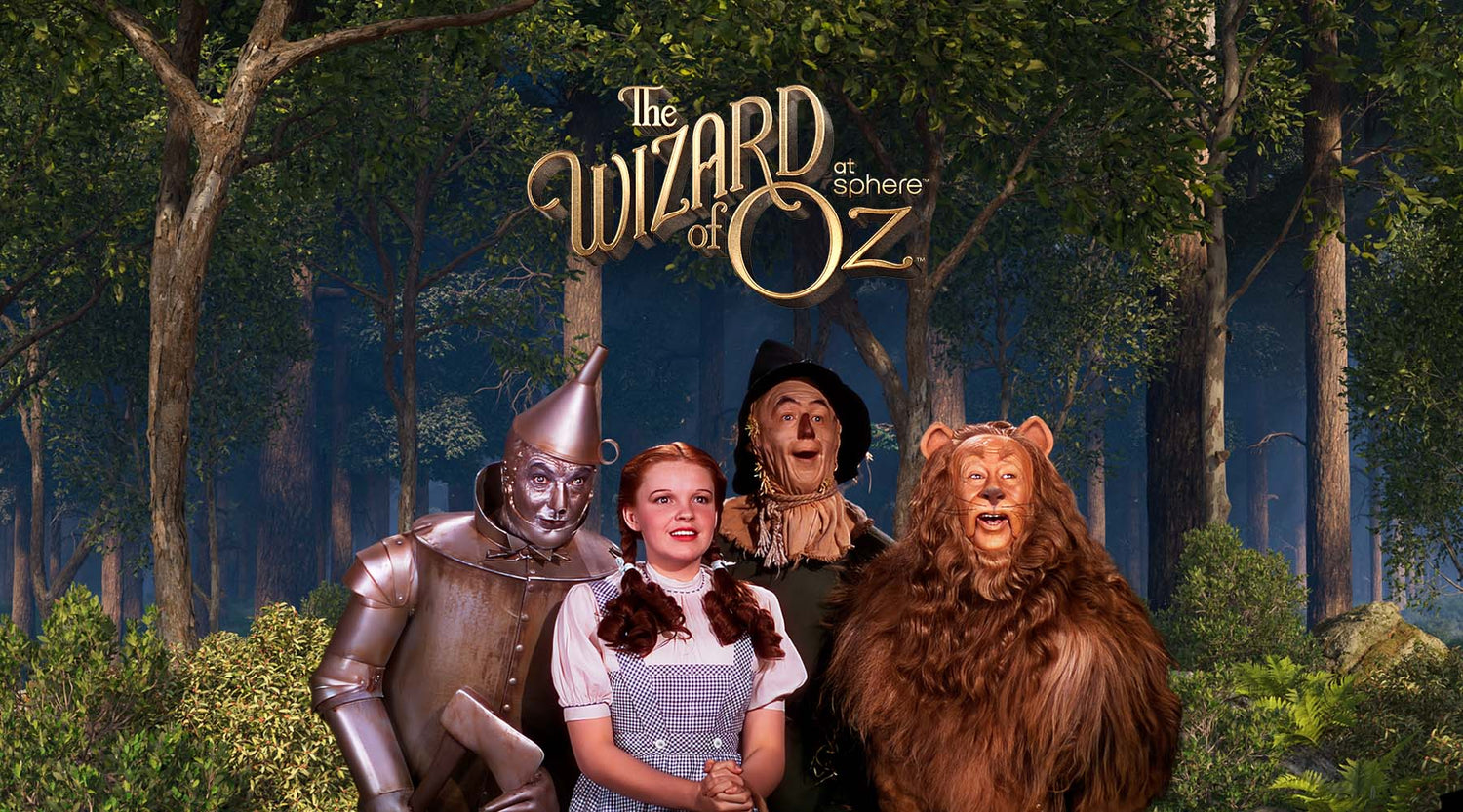 "The Wizard of Oz at Sphere" featuring The Tin Man, Dorothy, Scarecow and Cowardly Lion standing in front of a forest